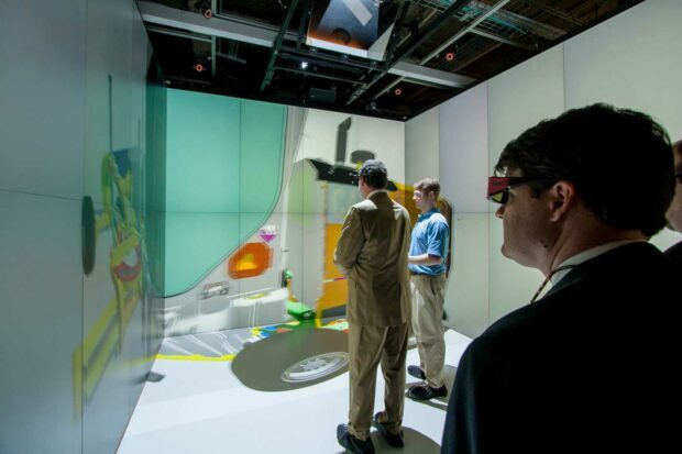 Men standing in a movable immersive video room to look at jet engine