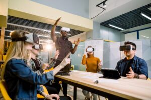 Enjoying new experience. Handsome young African man in VR headset gesturing and smiling while standing at the table. Young people wearing vr goggles.