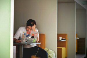 Man on laptop looking stressed out because he has not outsourced his service desk