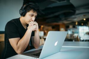 Dark haired man with headphones looking at his laptop
