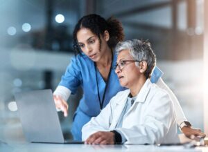 two healthcare professionals looking at a laptop