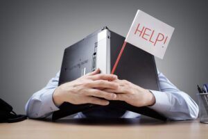 Man stressed covering his head with a laptop and holding a help sign