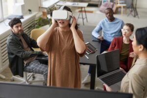 Diverse IT development team working on virtual reality software in office, focus on young woman wearing VR headset in foreground