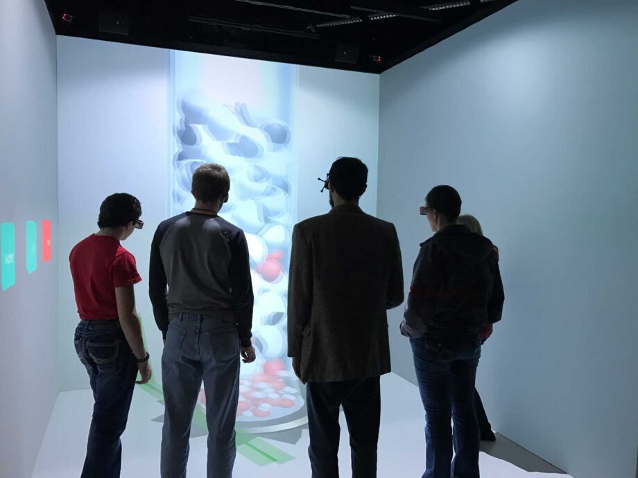 four people standing in an immersive virtual reality CAVE system