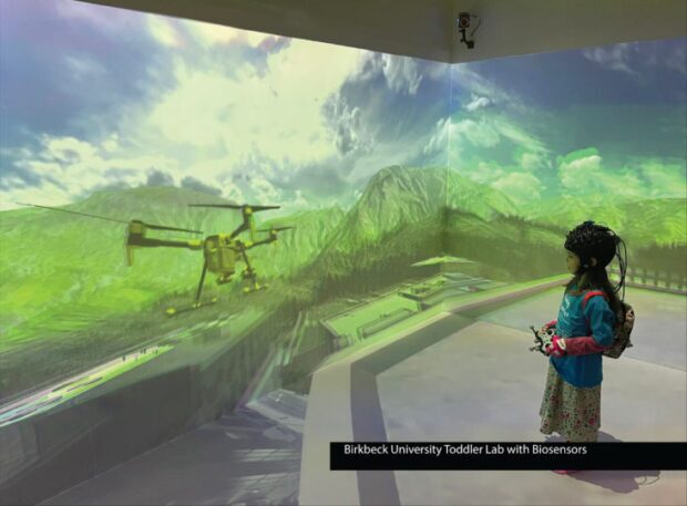 Four wall immersive virtual and extended reality CAVE with child wearing full sensor mesh for brain activity scan